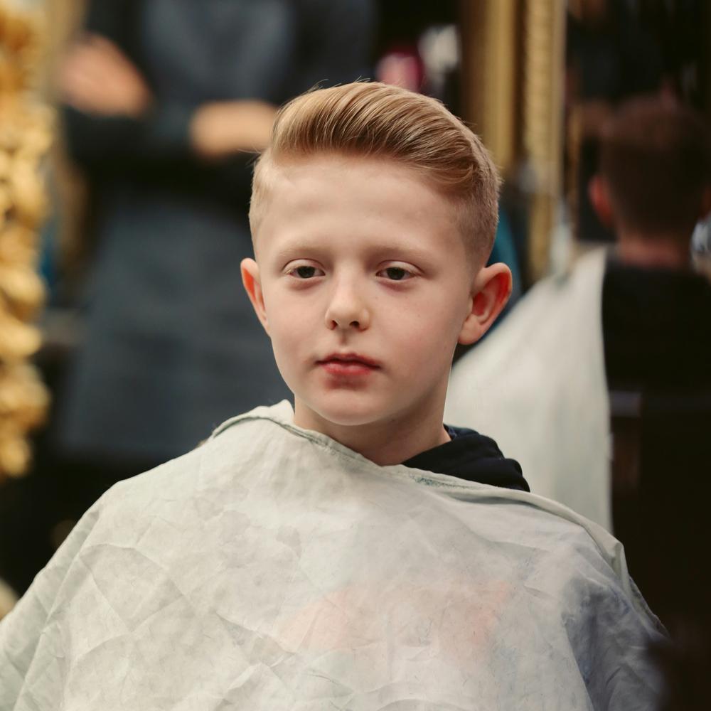 Chlapec s modern&iacute;m chlapeck&yacute;m &uacute;česem sed&iacute; v kadeřnictv&iacute;