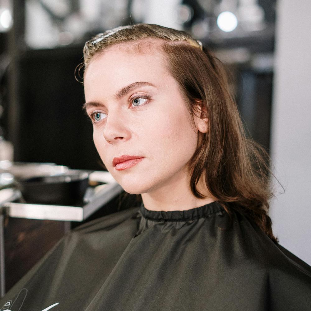 Žena v kadeřnick&eacute;m salonu s jemn&yacute;m ř&iacute;dnut&iacute;m vlasů u čela